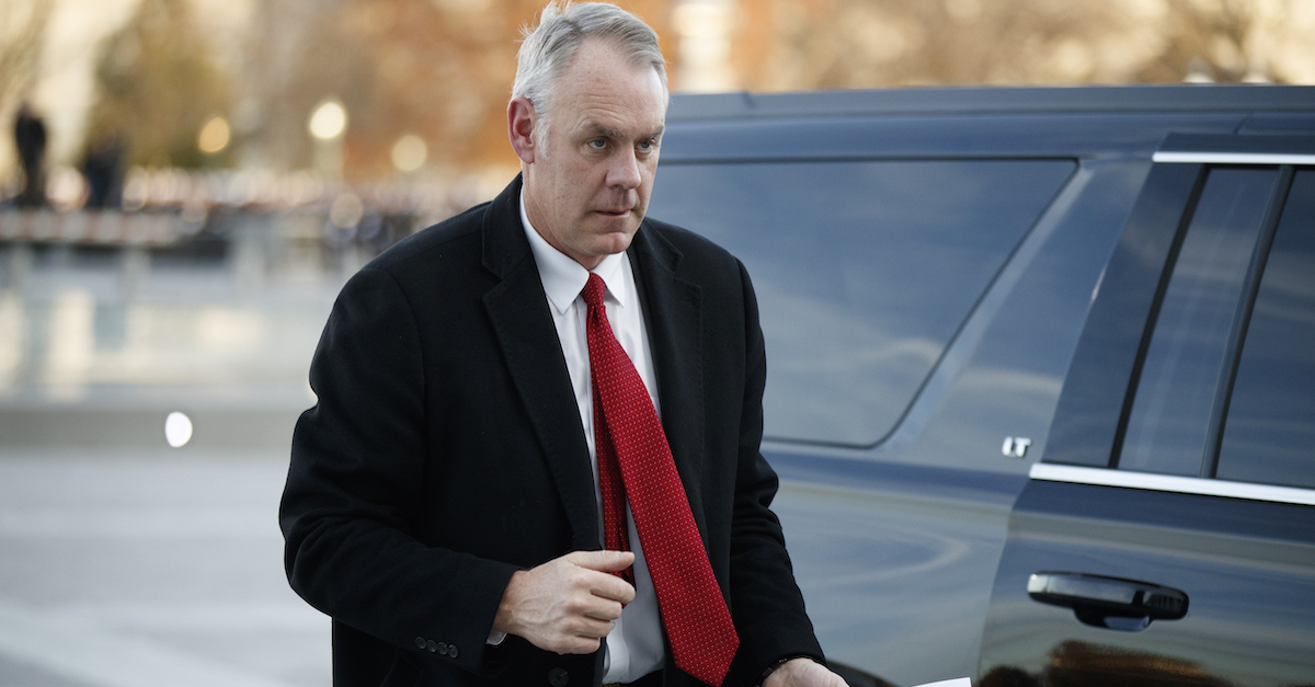 Ryan Zinke stands by a car