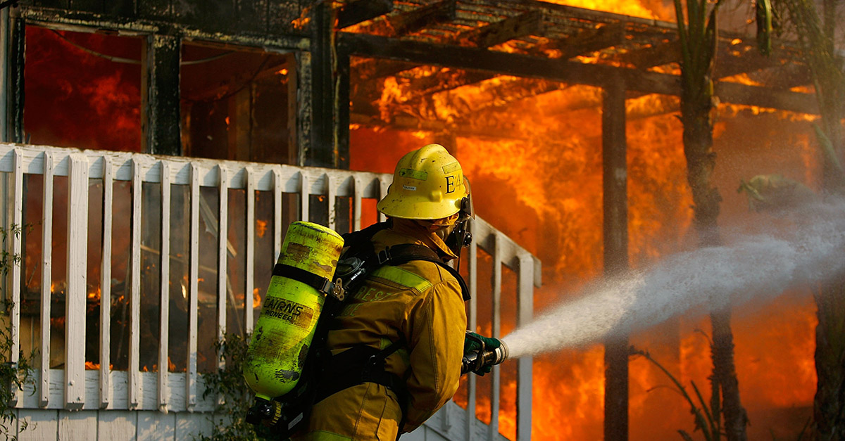 JAMUL, CA - OCTOBER 24: A US forestry firefighter cools a burning modular home to protect a nearby structure in Deerhorn Valley as the Harris Fire continues growing beyond 70,000 acres on October 24, 2007 near Jamul, California. Southern California is being ravaged by numerous record wildfires as Santa Ana Wind conditions push them into communities surrounded by native Chaparral habitat that has been dried by the driest rain season since records began 130 years ago. The fires are shaping up to be the worst wildfire event in San Diego County history. As many as 500,000 people have been evacuated from their homes. (Photo by David McNew/Getty Images)