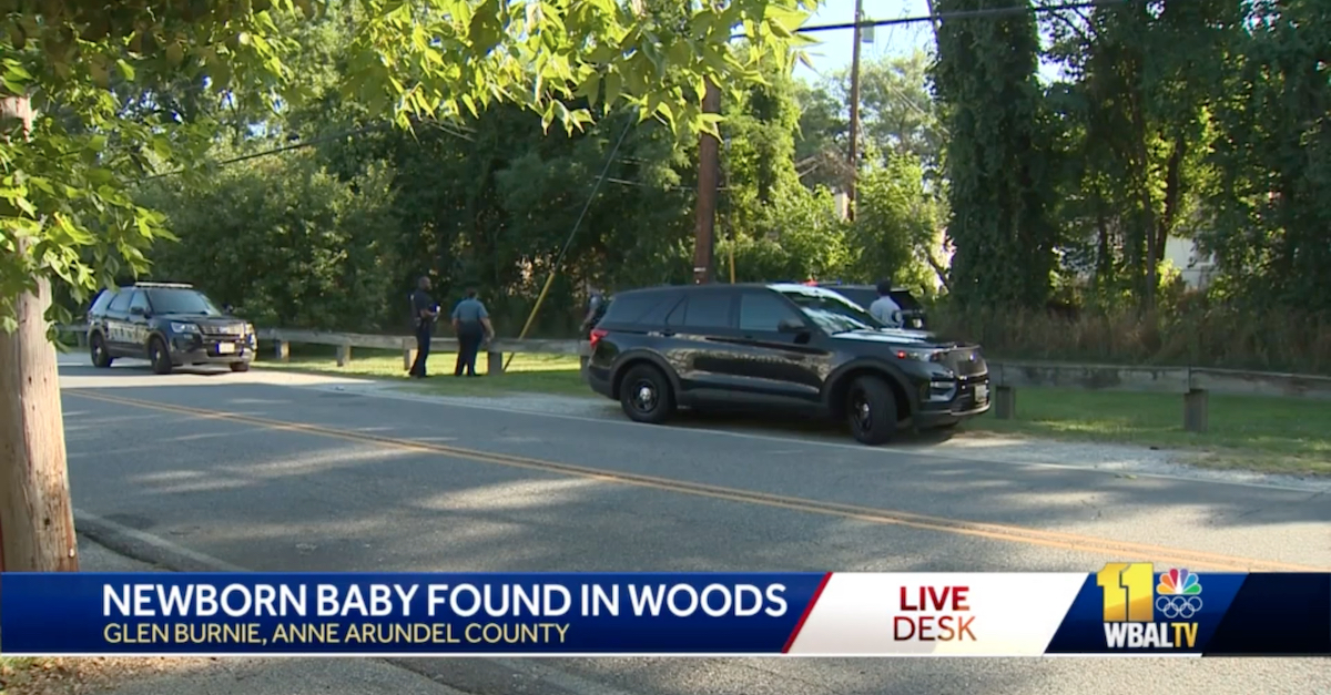 A picture shows police activity at the scene where a mother abandoned a newborn baby in a wooded area off a bike path near an intersection of two residential streets.