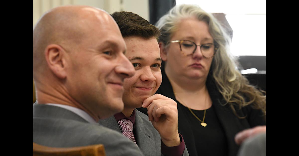 Kyle Rittenhouse (center) smirks while sitting in court on Nov. 9, 2021, flanked by his attorneys Corey Chirafisi (left) and Natalie Wisco (right). (Image © Mark Hertzberg/ZUMA Press Wire-POOL.)