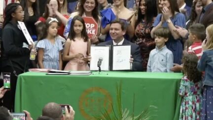 Ron DeSantis flanked by children at signing of Stop WOKE Act
