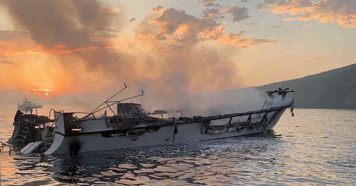 the shell of a burned boat at sunset