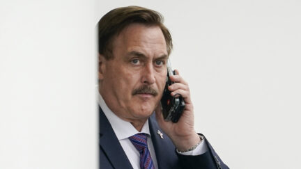A photo shows Mike Lindell holding his cell phone.