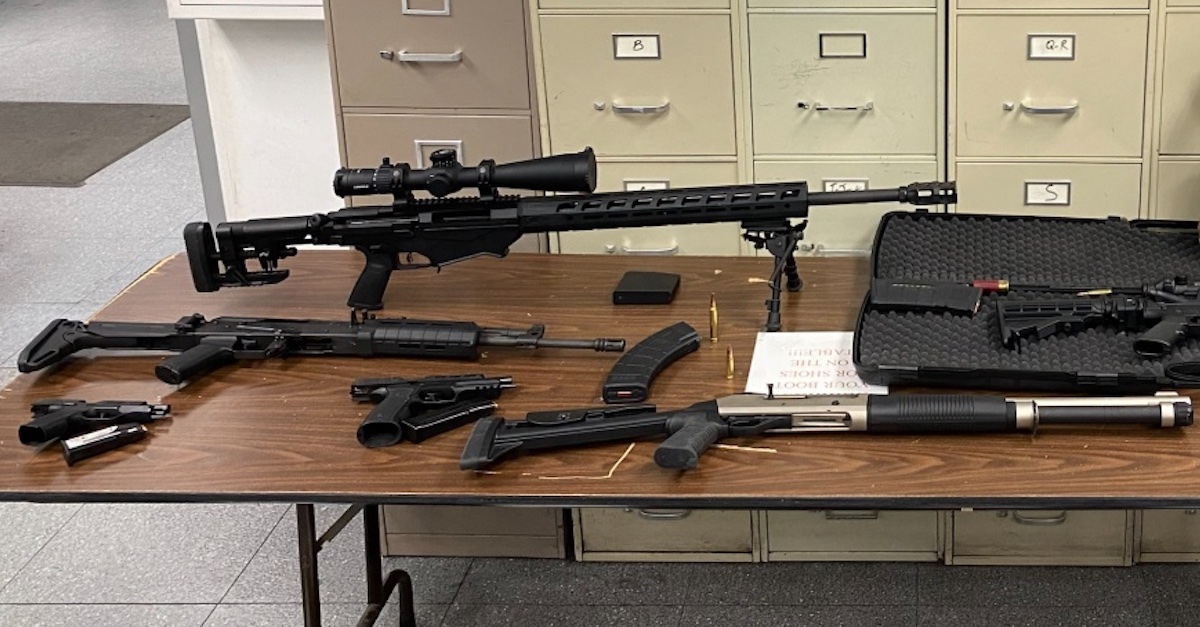 Several firearms and firearms parts are seen on a table.