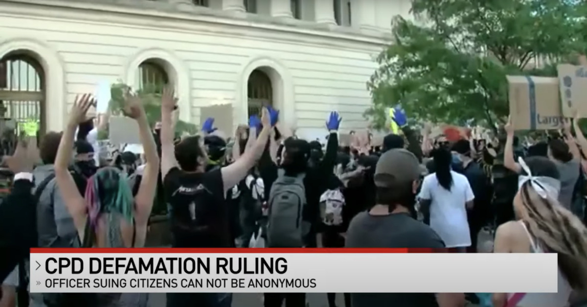 A screengrab from a local TV station showing Black Lives Matter demonstrators in Cincinnati in 2020; a chryron addresses a development in a case where a police officer unsuccessfully sued activists for calling him a racist.