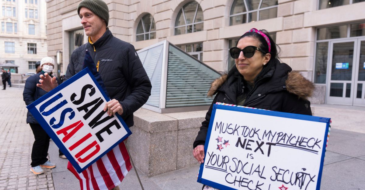 Priya Kathpal, right, and Taylor Williamson, who work for a company doing contract work for the United States Agency for International Development, or USAID, carry signs outside the USAID headquarters in Washington, Monday, Feb. 10, 2025. (AP Photo/Manuel Balce Ceneta)
